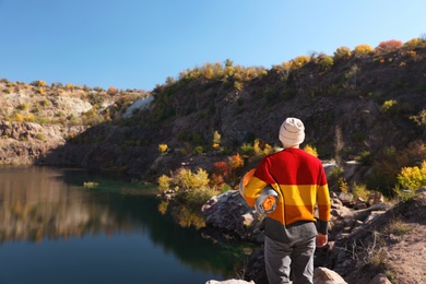 Male camper with sleeping bag near beautiful lake. Space for text