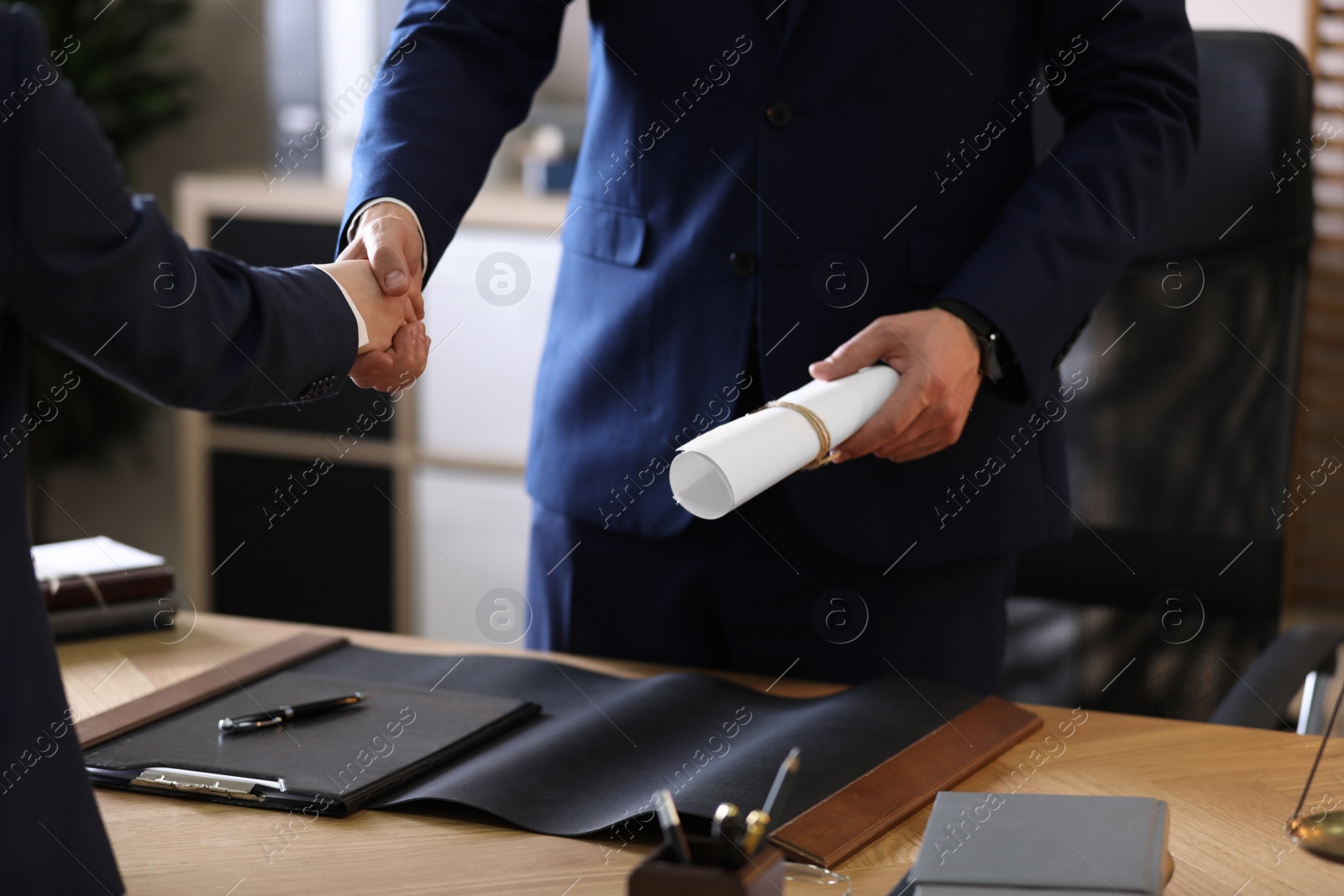 Photo of Male lawyer shaking hands with client in office, closeup