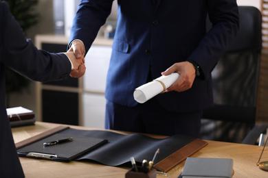 Male lawyer shaking hands with client in office, closeup