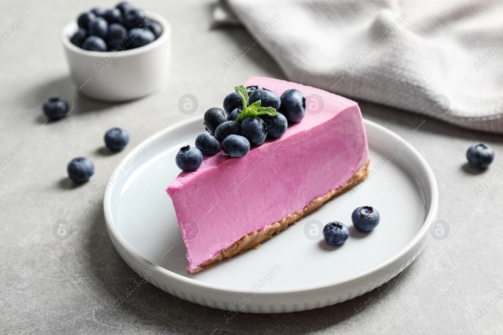 Photo of Plate with piece of tasty blueberry cake on light table