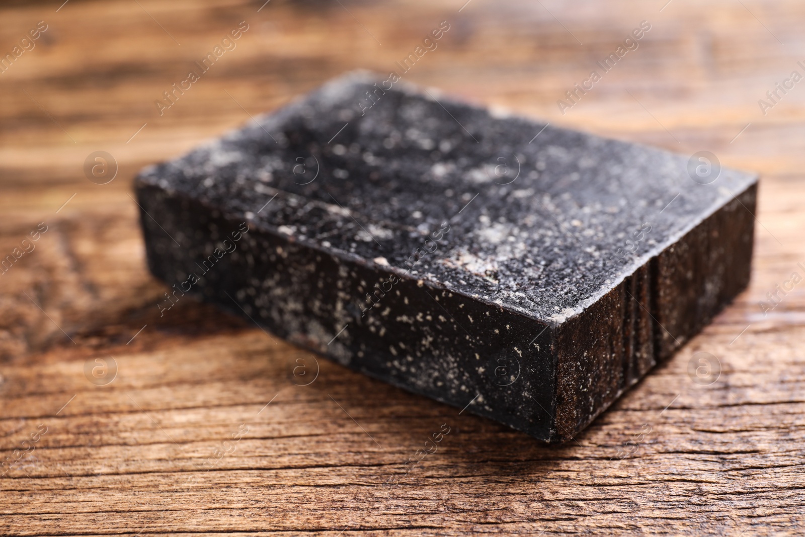 Photo of Natural tar soap on wooden table, closeup