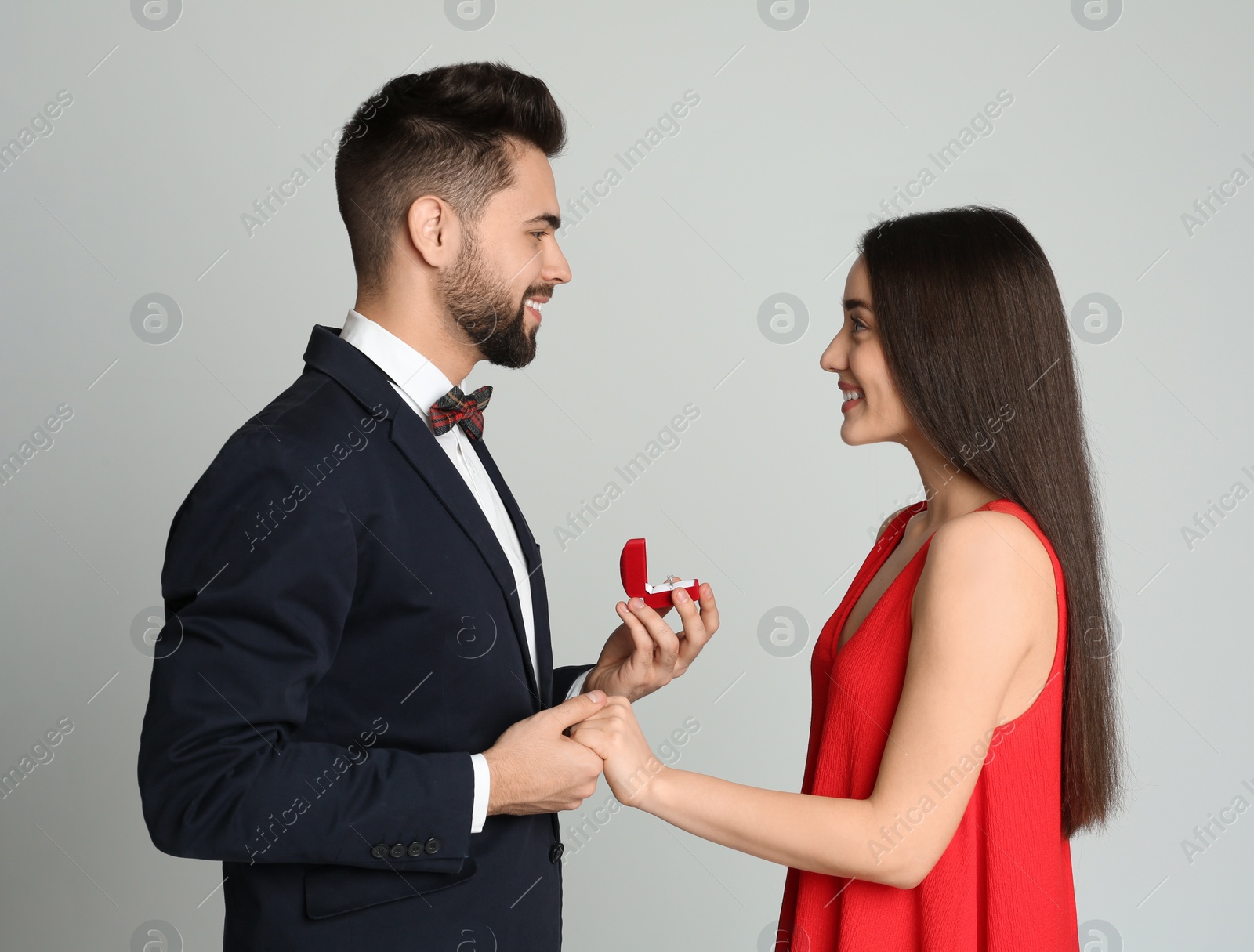 Photo of Man with engagement ring making marriage proposal to girlfriend on light grey background