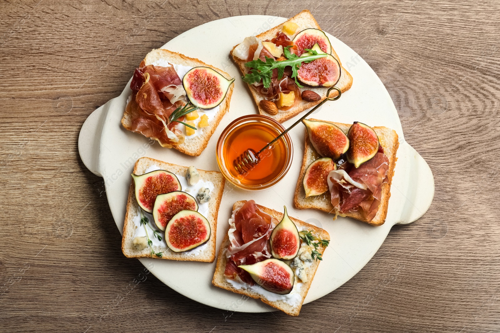 Photo of Sandwiches with figs, proscuitto and cheese on wooden table, top view