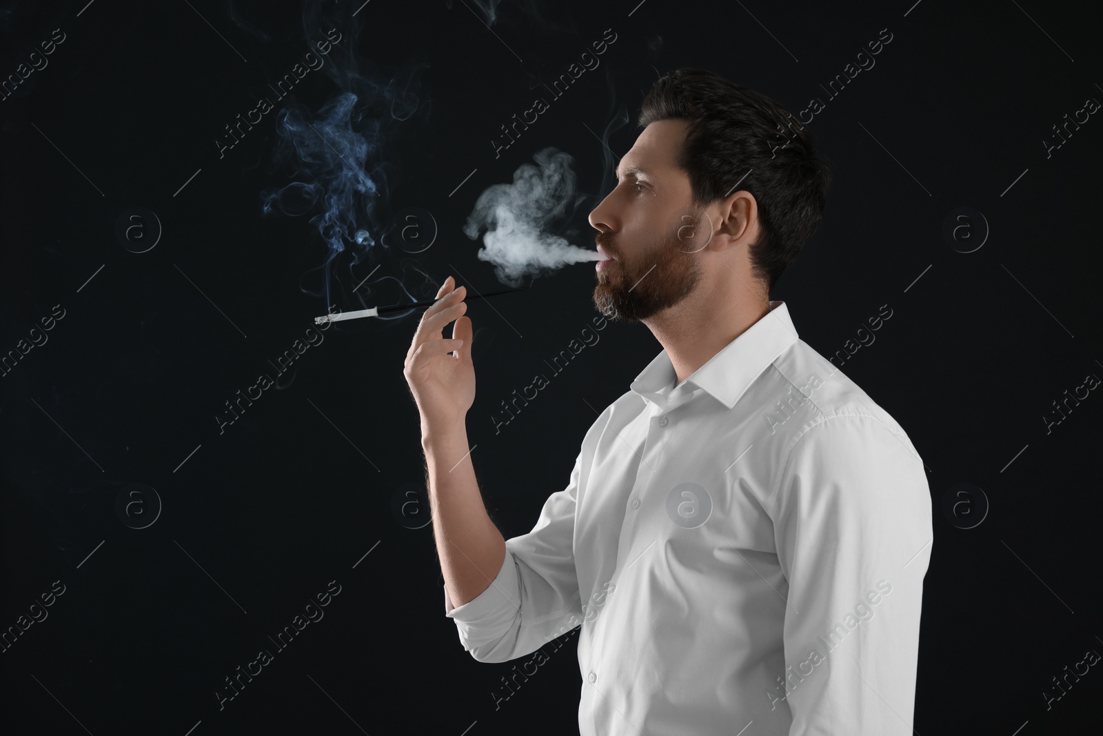 Photo of Man using long cigarette holder for smoking on black background