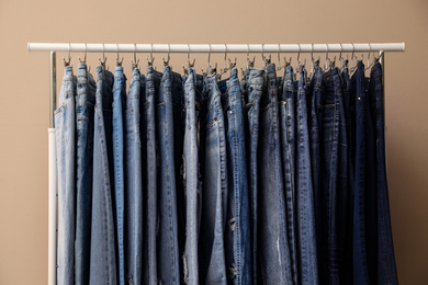 Photo of Rack with stylish jeans on beige background