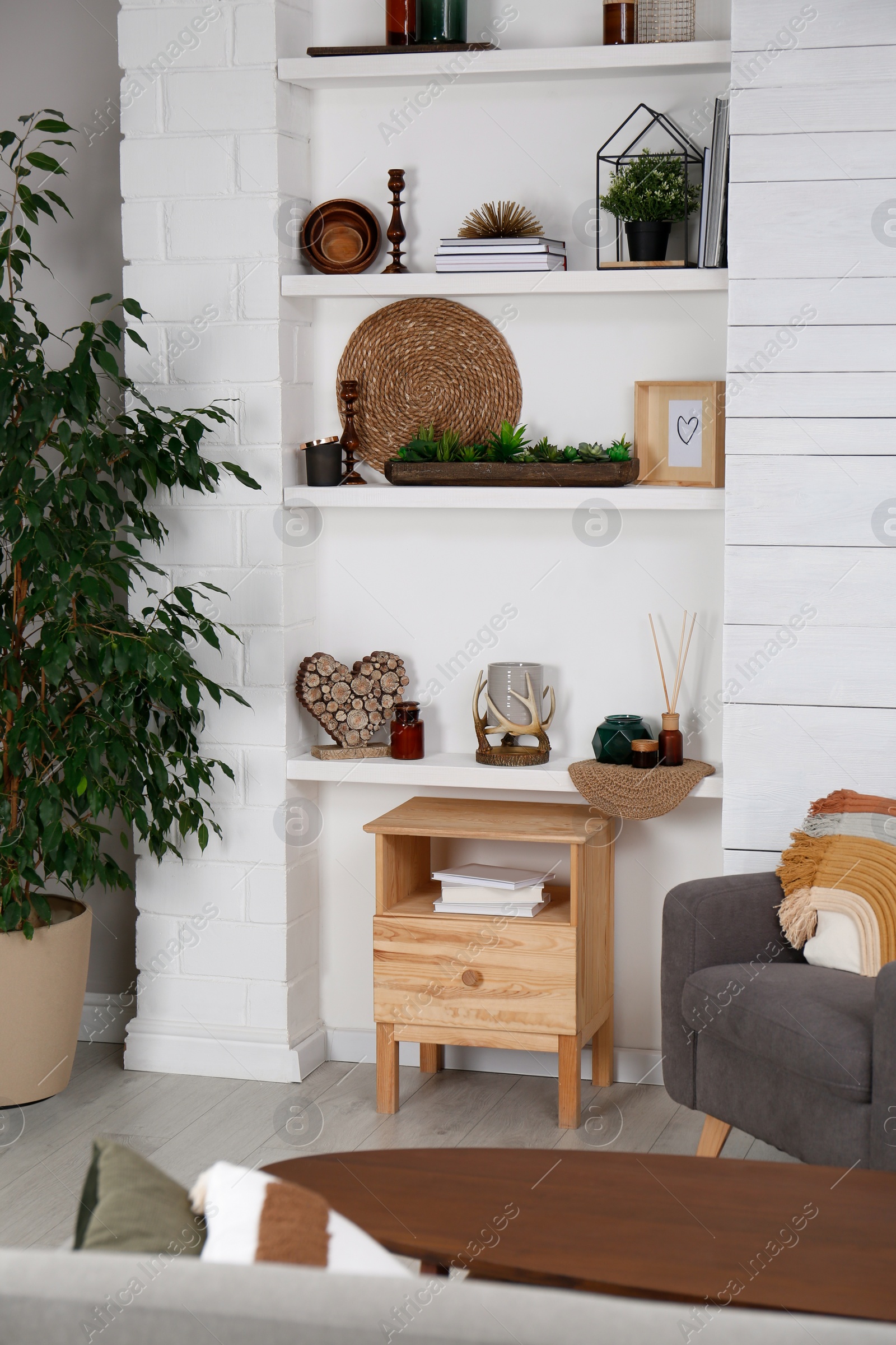 Photo of Stylish living room interior with comfortable armchair, wall shelves and beautiful decor elements