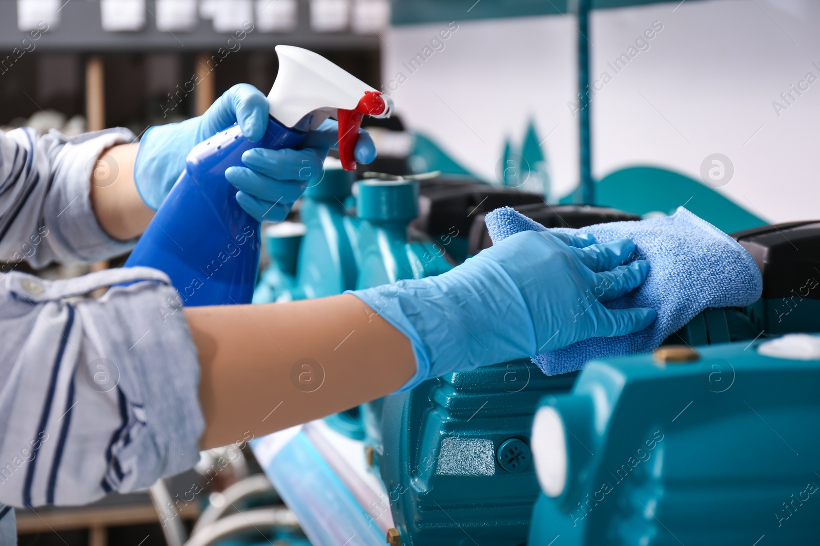 Photo of Woman cleaning water pump with rag and detergent in bathroom fixtures store, closeup