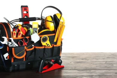 Photo of Bag with different tools on wooden table against white background