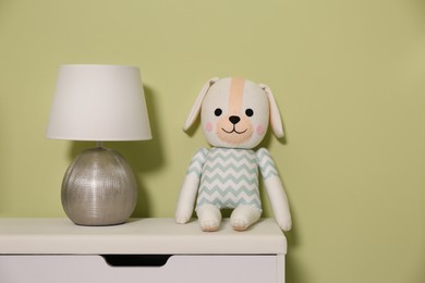 Stuffed toy and lamp on table near green wall. Interior design