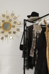 Rack with stylish women's clothes and accessories near white wall in dressing room