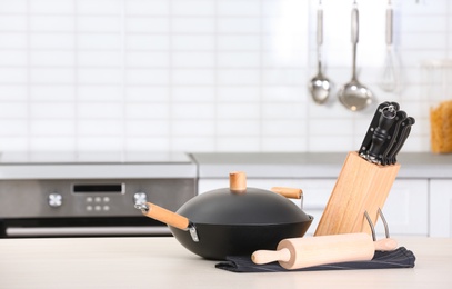 Photo of Set of clean cookware and utensils on table in kitchen. Space for text