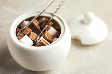 Different refined sugar cubes in bowl on light table