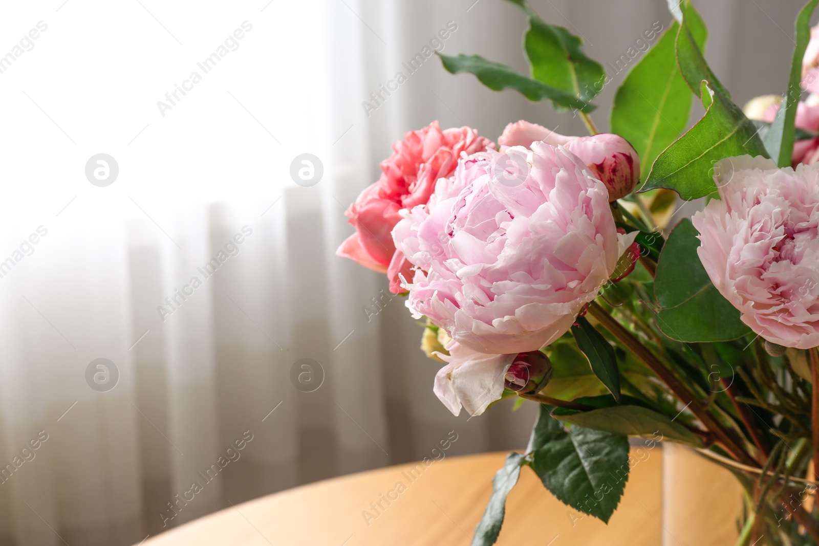 Photo of Beautiful flower bouquet in vase on table near window at home. Space for text