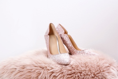 Photo of Stylish female shoes on fur against light background