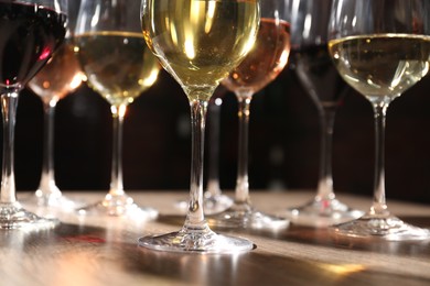 Photo of Different tasty wines in glasses on wooden table