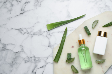 Flat lay composition with aloe vera and cosmetic products on white marble background. Space for text