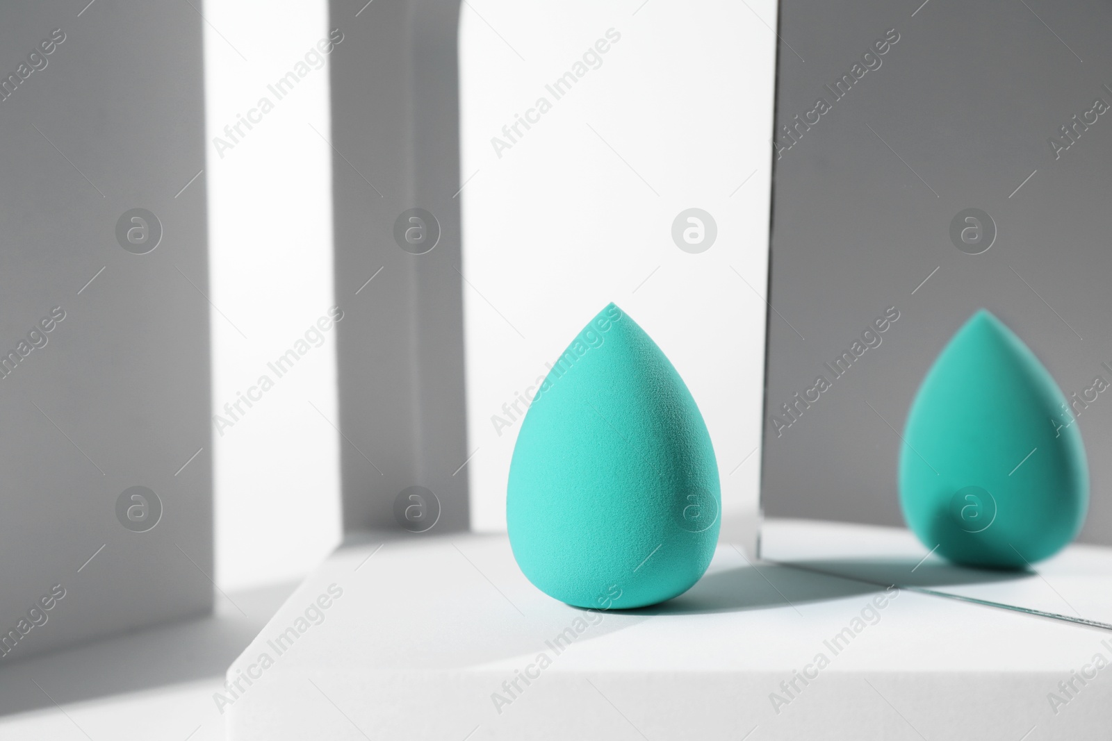 Photo of Stylish presentation of turquoise makeup sponge on white background, space for text