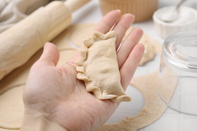 Woman holding dumplings (varenyky) with cottage cheese at white table, closeup