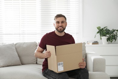 Happy young man with parcel at home