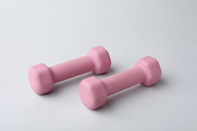 Photo of Two pink rubber coated dumbbells on light background