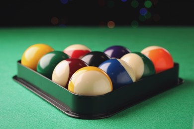 Photo of Billiard balls in triangle rack on green table, closeup