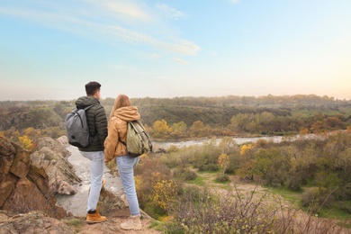 Couple of hikers with travel backpacks enjoying beautiful view near mountain river