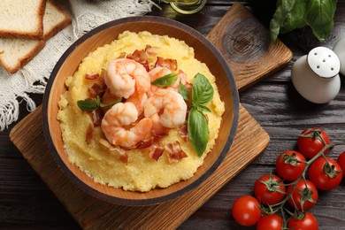 Photo of Fresh tasty shrimps, bacon, grits and basil in bowl on wooden table, flat lay