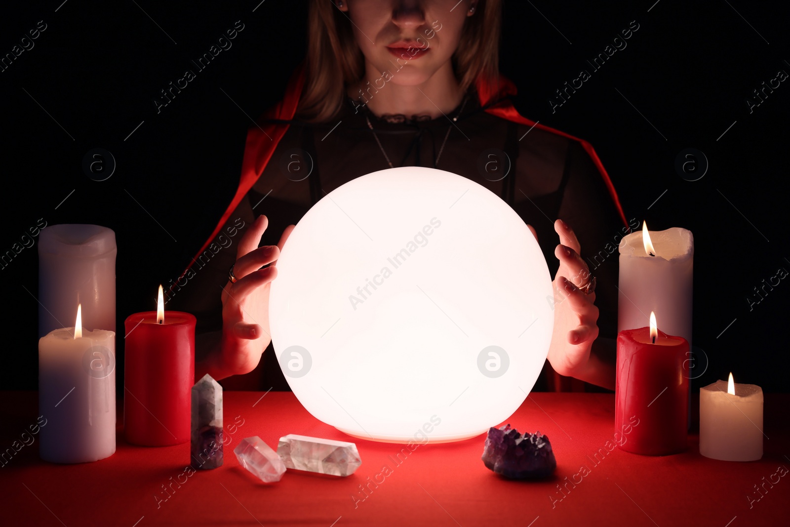 Photo of Soothsayer using glowing crystal ball to predict future  at table in darkness, closeup. Fortune telling