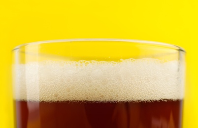 Photo of Delicious homemade kvass in glass on yellow background, closeup