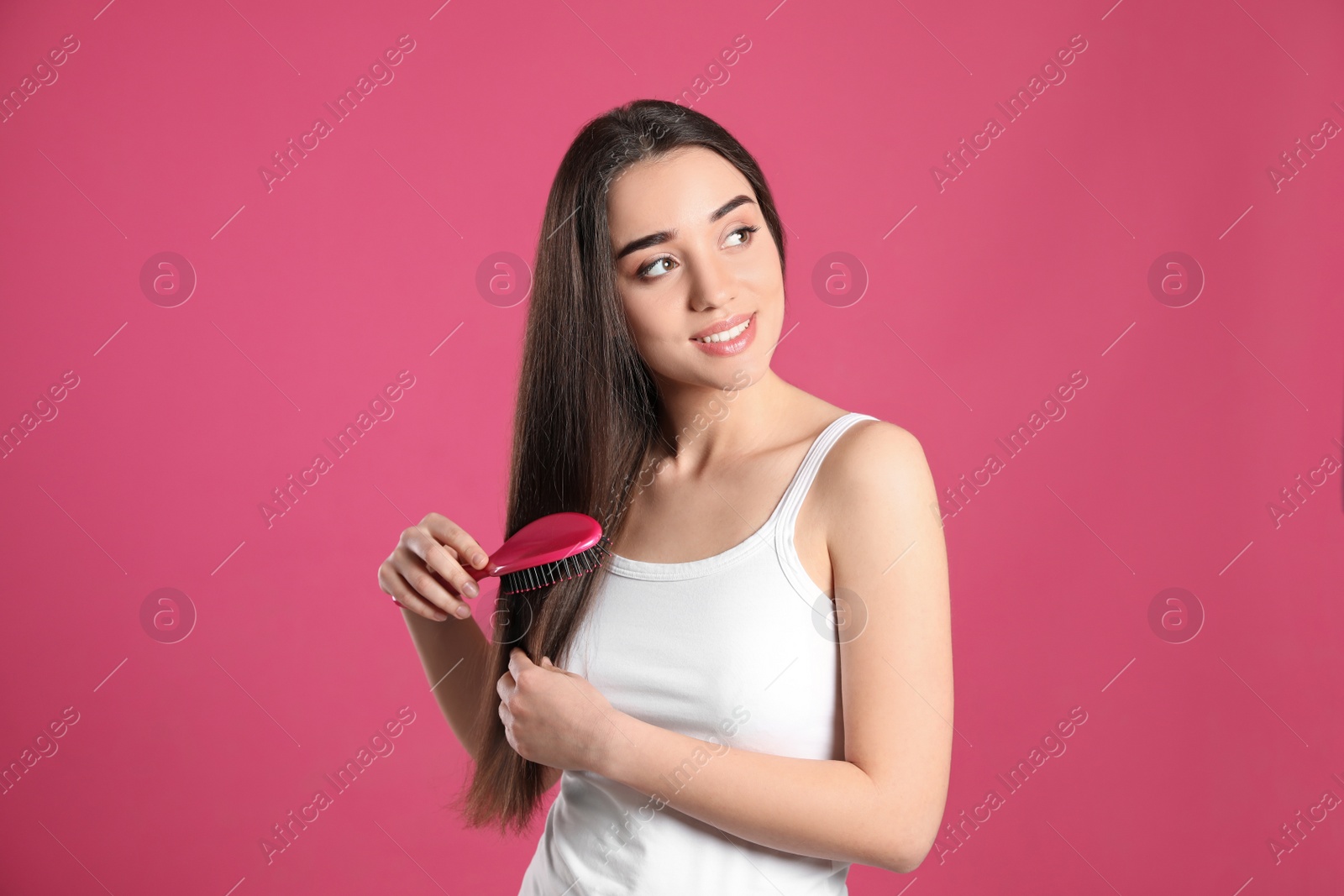 Photo of Beautiful smiling young woman with hair brush on color background