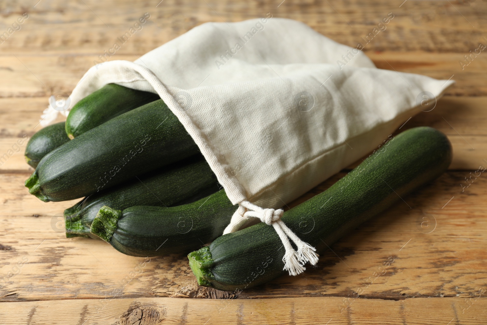 Photo of Sack with green ripe zucchinis on wooden table