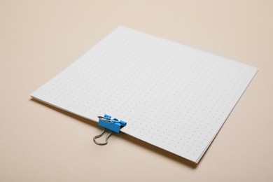 Photo of Sheet of paper with clip on beige background