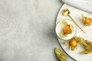 Delicious dessert decorated with physalis on light grey table, flat lay. Space for text