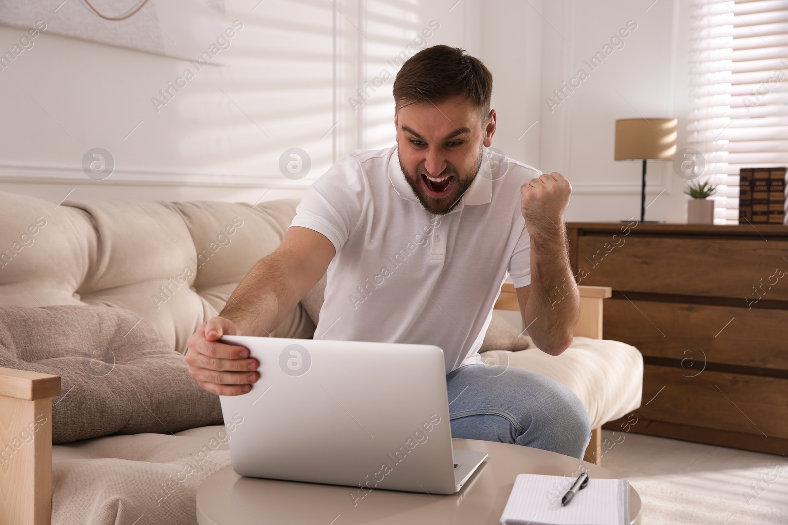 Photo of Emotional man participating in online auction using laptop at home