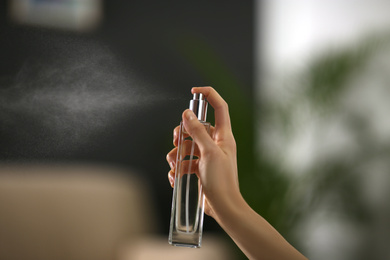 Woman spraying air freshener at home, closeup