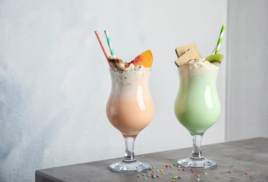 Photo of Glasses with delicious milk shakes on table against light background