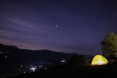 Photo of Beautiful view of mountain landscape with glowing yellow camping tent at night