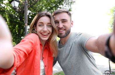 Happy young couple taking selfie in park