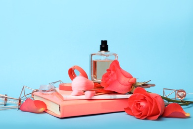 Composition with coral notebooks, flowers and perfume on light blue background