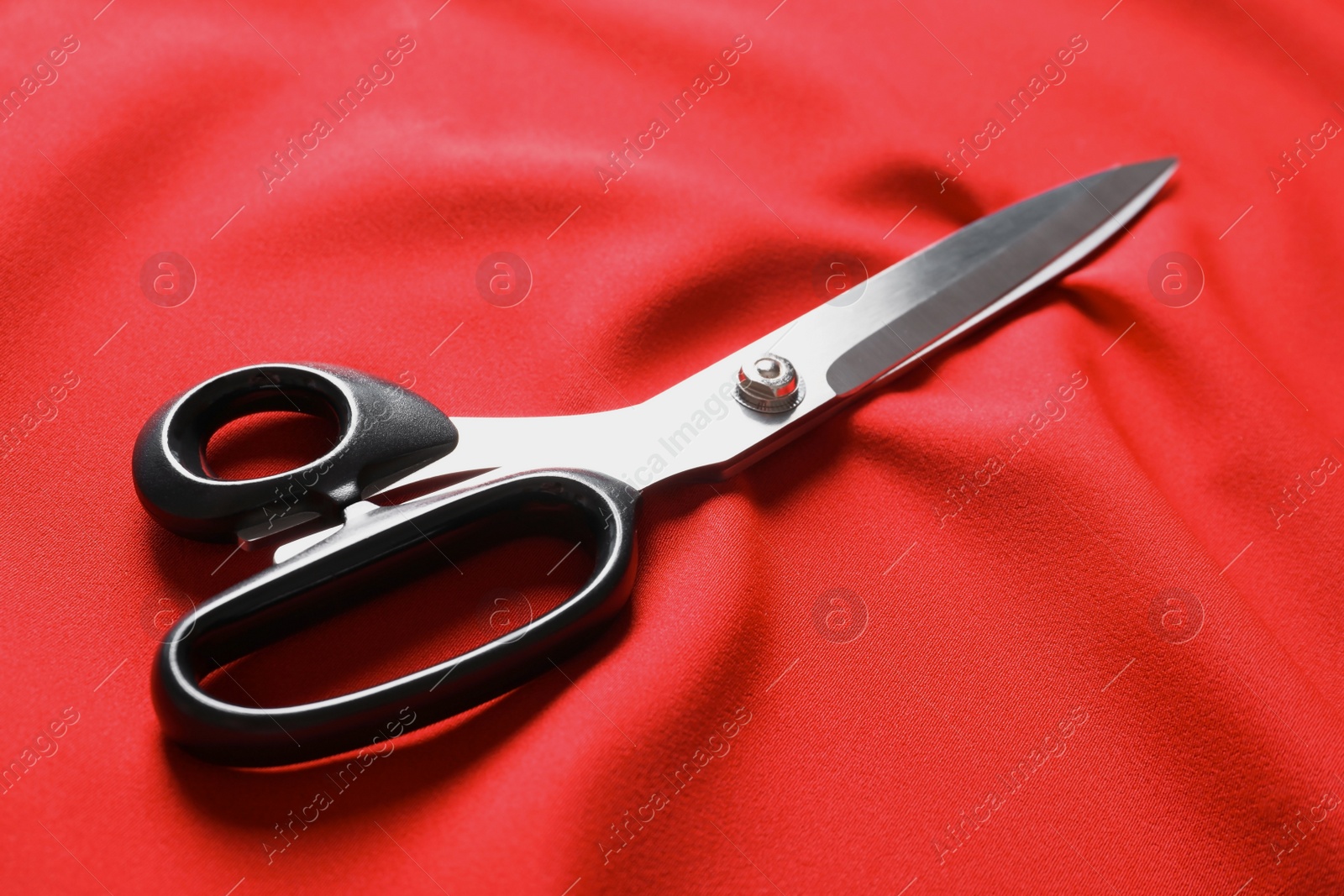 Photo of Scissors on red fabric. Tailoring accessories