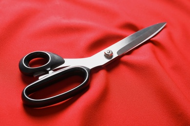 Photo of Scissors on red fabric. Tailoring accessories