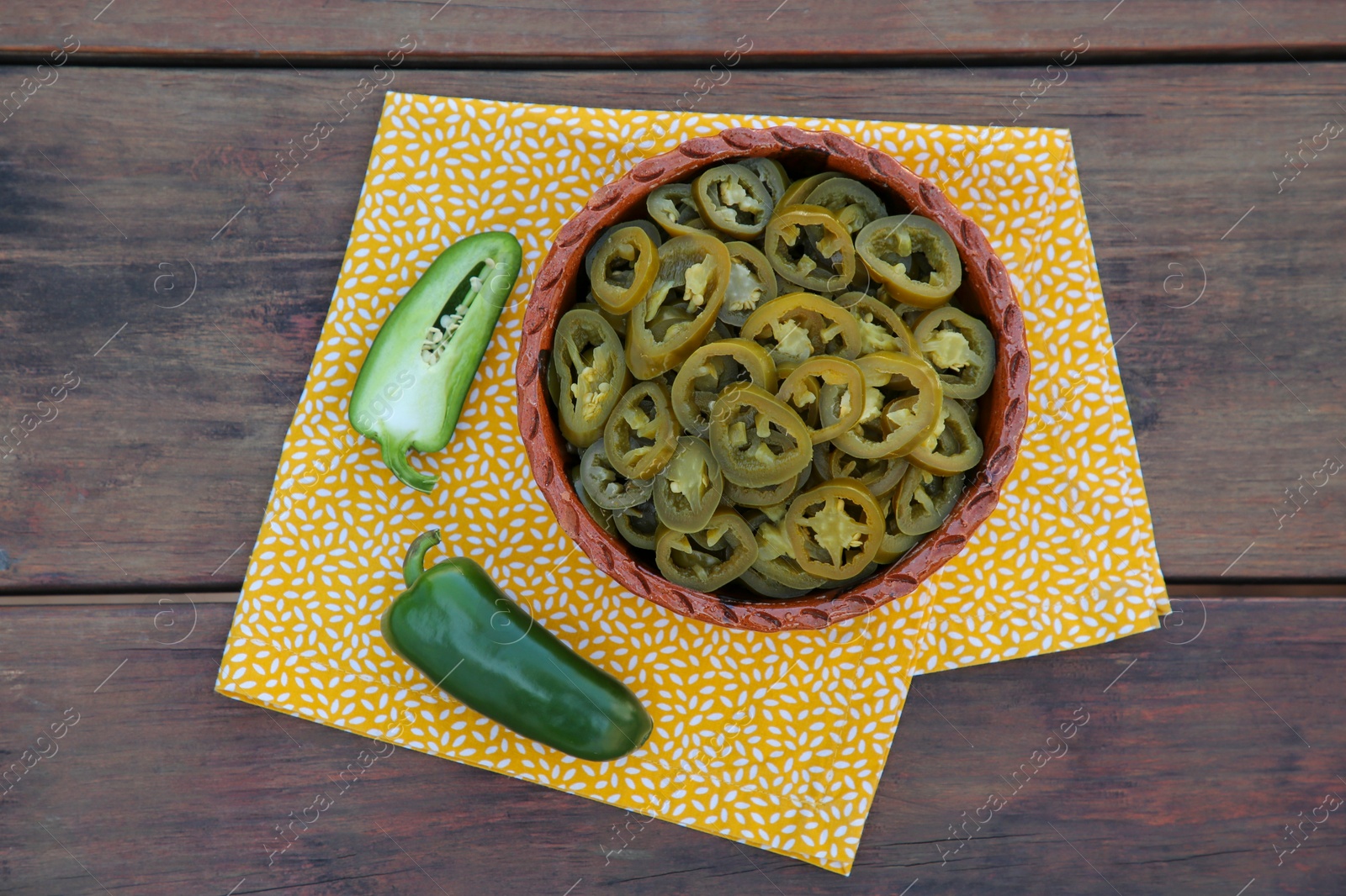 Photo of Fresh and pickled green jalapeno peppers on wooden table, top view