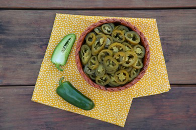 Fresh and pickled green jalapeno peppers on wooden table, top view