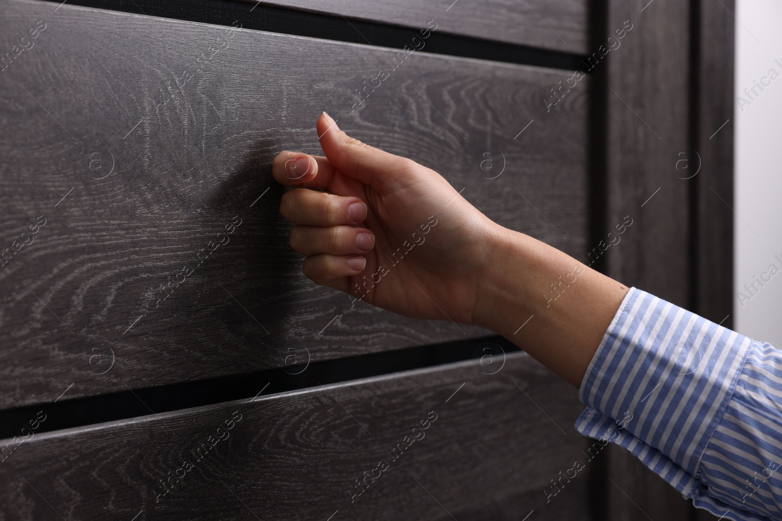 Photo of Woman knocking on door indoors, closeup view