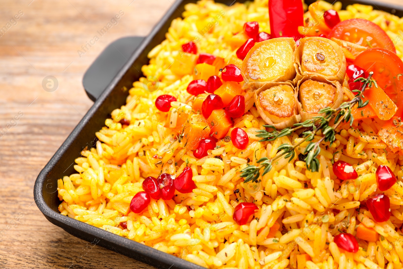 Photo of Tasty rice pilaf with vegetables on wooden table, closeup