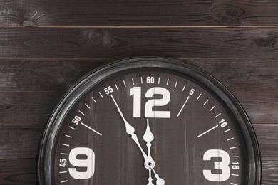 Photo of Stylish analog clock hanging on wooden wall. New Year countdown