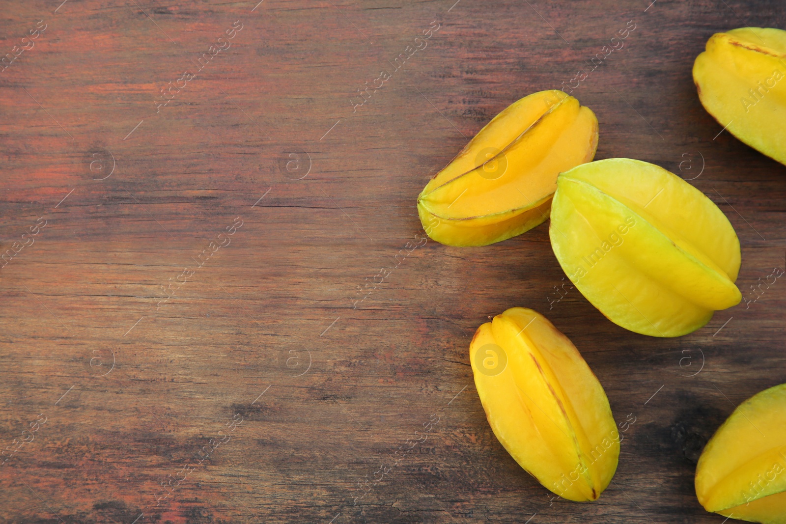 Photo of Delicious ripe carambolas on wooden table, flat lay. Space for text