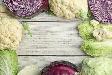 Flat lay composition with different cabbages on wooden background