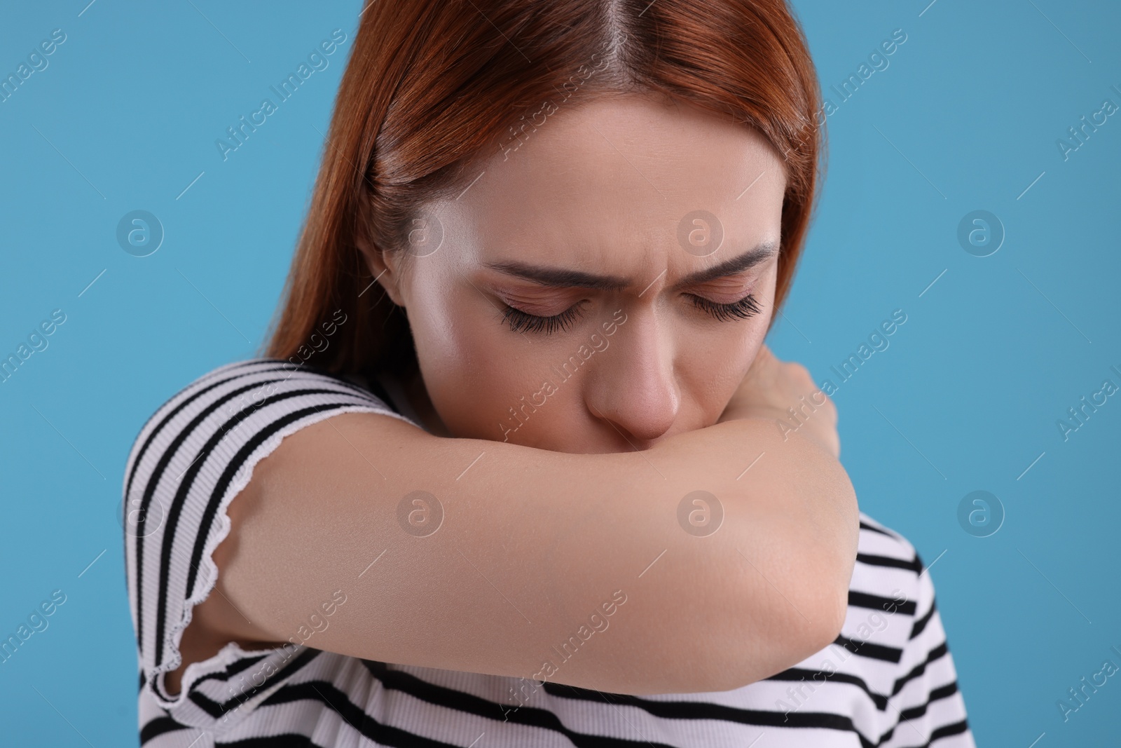 Photo of Woman coughing on light blue background. Cold symptoms