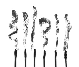 Photo of Different brushes and mascara strokes on white background